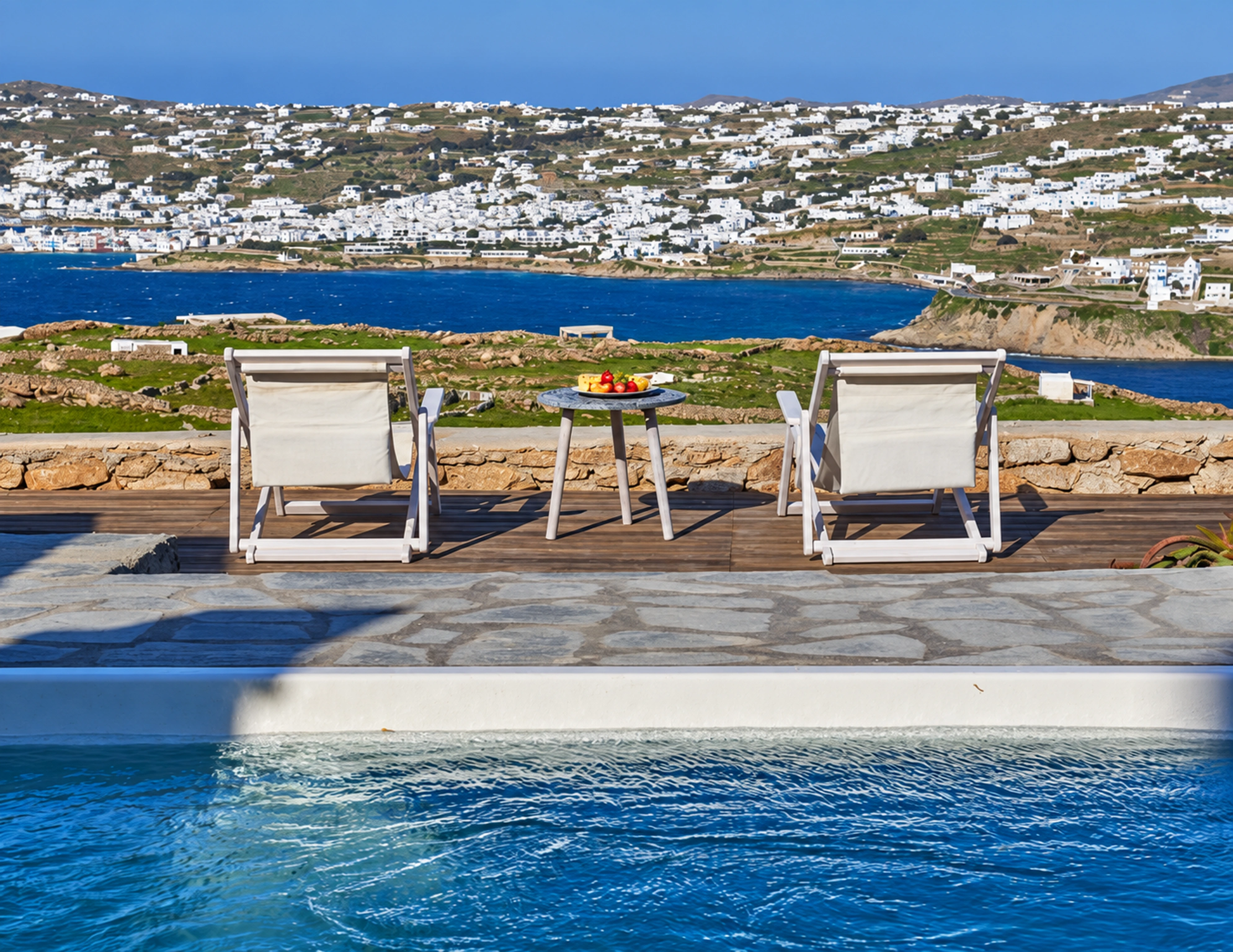 The villa’s rectangular private pool and loungers overlooking Mykonos