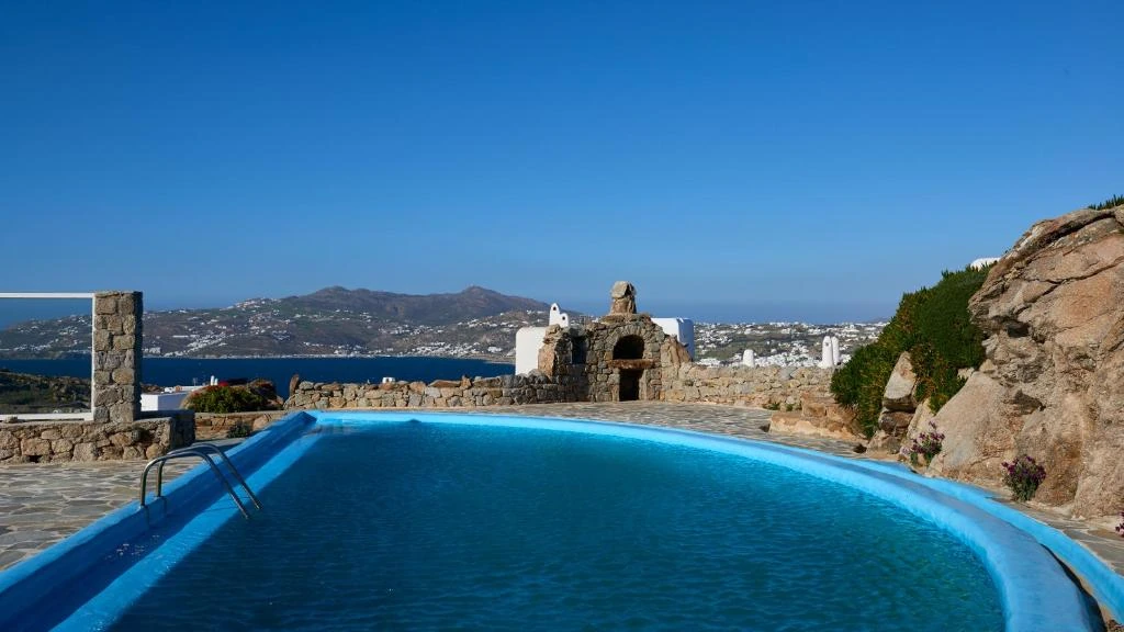 One of the complex’s shared swimming pools beside natural stone and an Aegean view